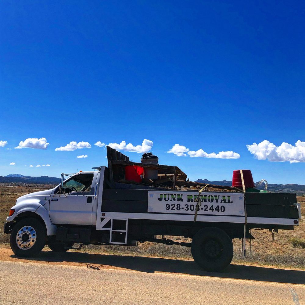 True West junk removal truck loaded with scrap lumber on a desert road