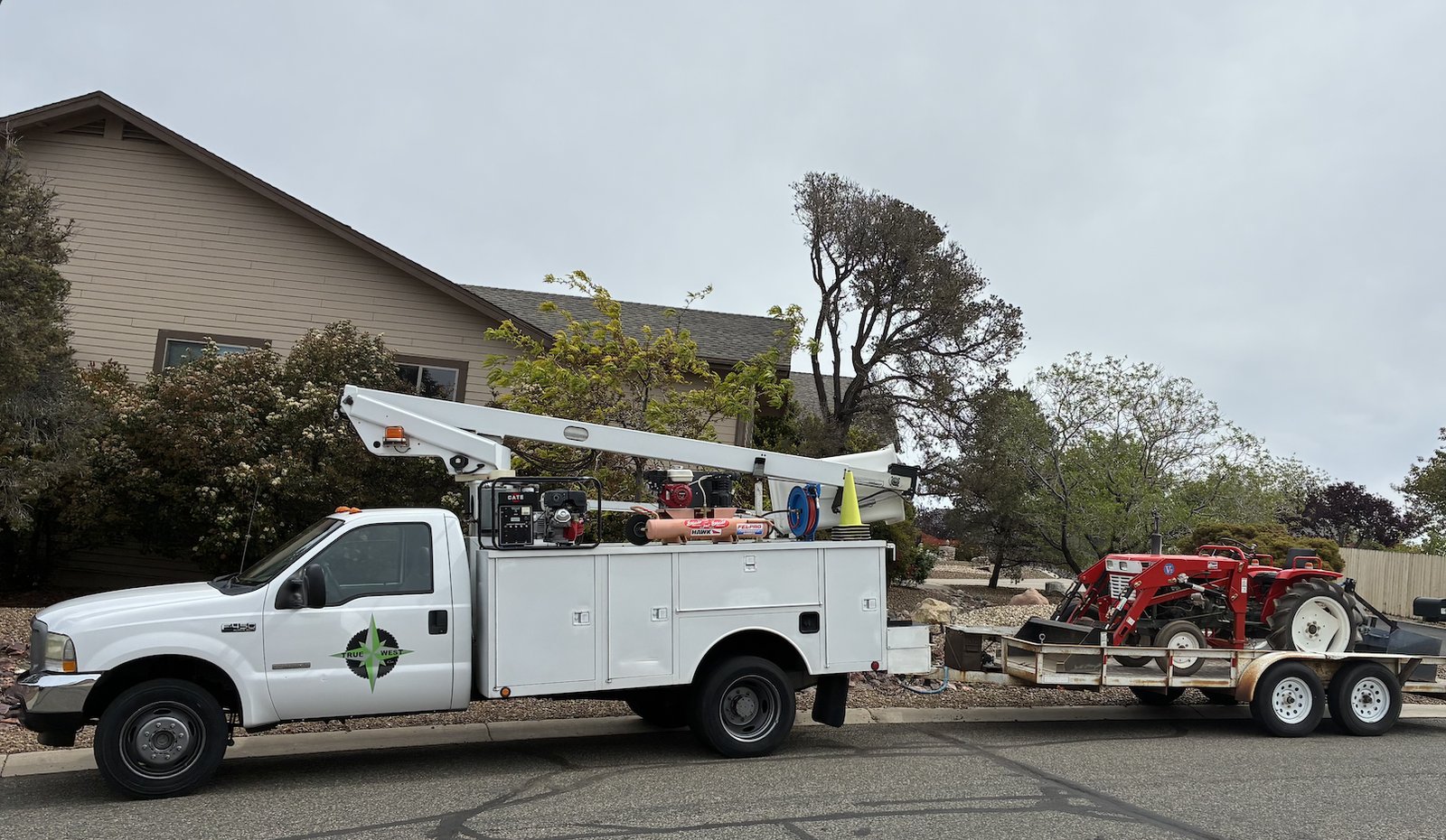 True West Co. service truck with bucket lift and trailer-mounted tractor